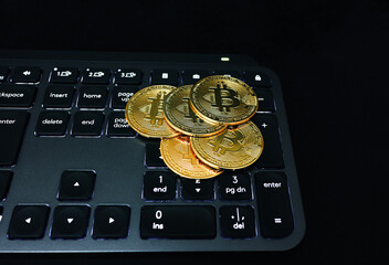 Gold Bitcoin Coins on Computer Keyboard in Dark Setting Stack of Cryptocurrency Coins Placed on Laptop Keyboard