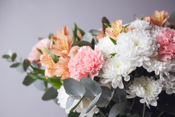 Pastel bouquet of flowers on a light background. Floral arrangement of alstroemeria buds, carnations, and chrysanthemums with eucalyptus branches. Floral background for a spring card, flower shop