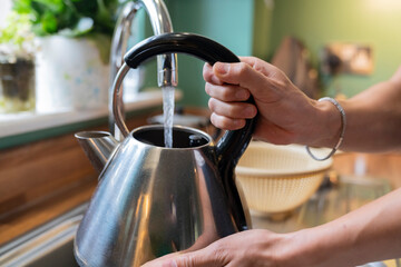 Anonymous Man Fills Electric Kettle With Water in Home Kitchen