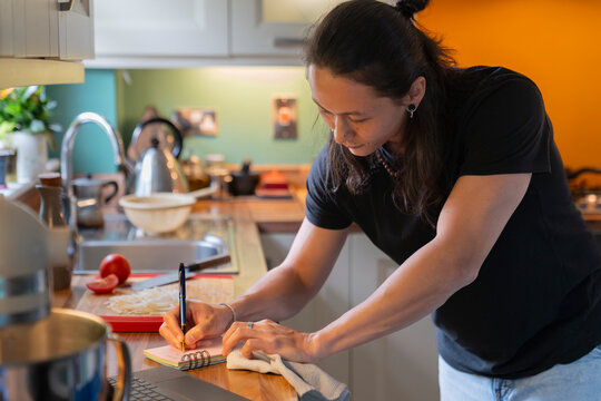 Young Man Writing a Grocery List in His Kitchen at Home