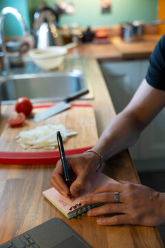 Anonymous Man Writing Grocery List in Home Kitchen With Tablet Support