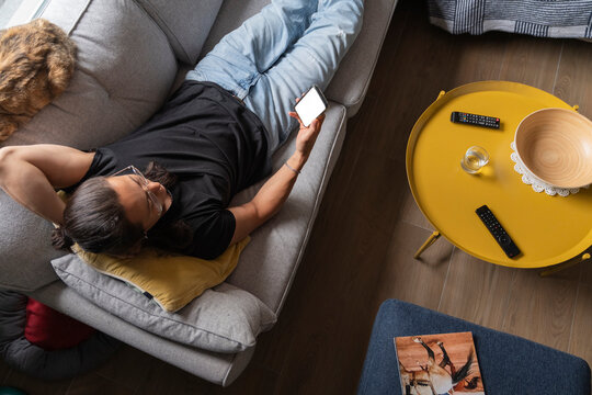 Man Relaxing on Couch While Watching Content on Mobile Device