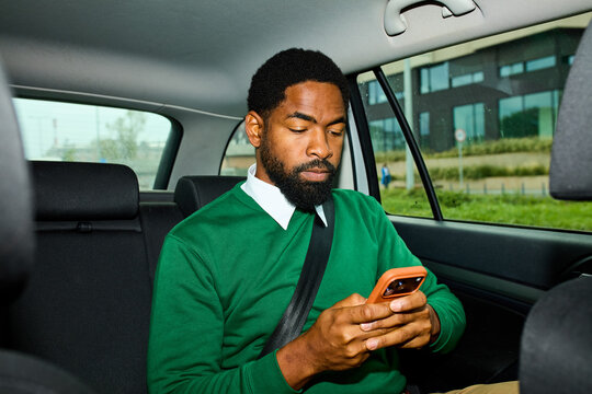 Man sending texts via his phone in a car