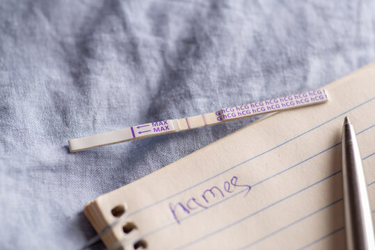 Positive pregnancy test and notebook with pen