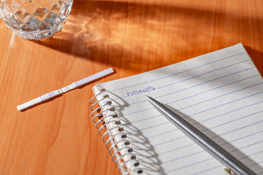 Positive pregnancy test and notebook with pen