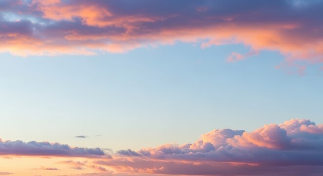 Delicate pastel colored clouds frame clear blue sky space during twilight