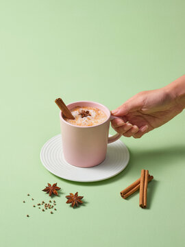 Hand Holding Latte in Pink Mug with Cinnamon and Star Anise Garnish
