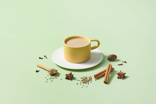 Yellow Mug of Spiced Tea with Ingredients on Green Background