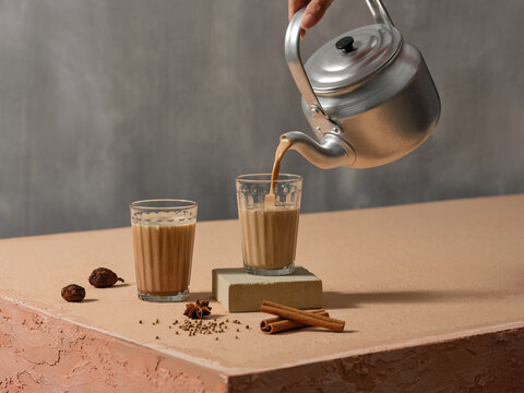 Traditional Masala Chai Tea Being Poured from Kettle into Glasses - Powered by Adobe