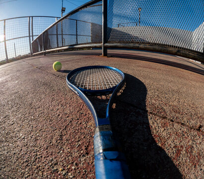 Tennis Racket and Ball on Court During Bright Sunny Day