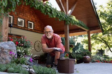 Smiling older man gardening on a sunny porch with plants