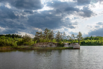 Obraz premium Serene landscape featuring a tranquil lake surrounded by lush greenery and scattered clouds above