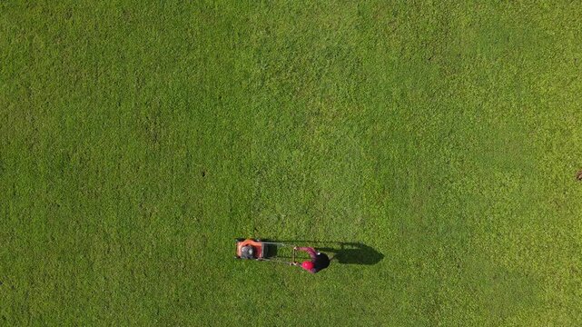 Drone Footage of Groundskeeper Mowing Grass on a Football Field