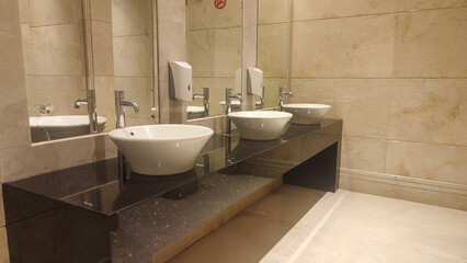 Contemporary interior of public toilet, modern and clean public toilet sink area equipped with large mirror