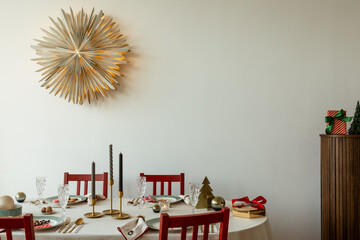 Festive dining table decorated with red chairs, gold accents, candles, and Christmas ornaments in a...