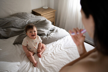 Baby Smiles While Adult Brushes Teeth in a Cozy Bedroom