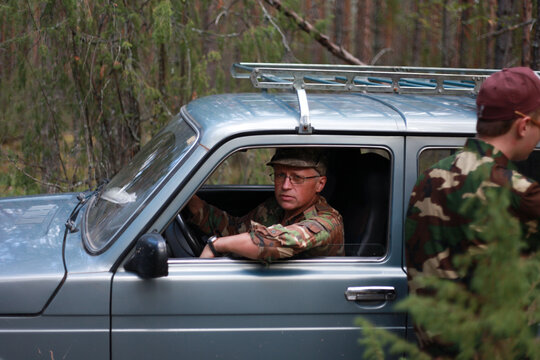 Man in camouflage sitting in offroad car in forest