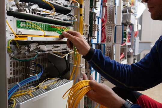 A Technician is Focused on Connecting Wires in a Communication Room
