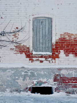 Old brick wall with sealed window and winter snow