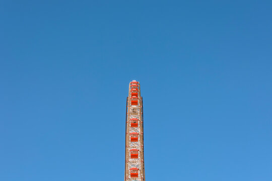 Minimalist Vertical Line: Ferris Wheel Against a Blue Sky.