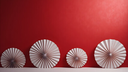 White paper fan decorations arranged by size on a red wall and white surface symmetrical, festive, and perfect for cultural or celebratory design themes.