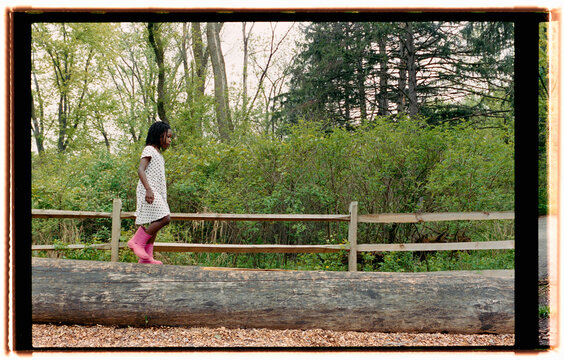 Child Walking on a Log Wearing Pink Boots