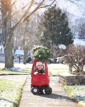 Child In Red Toy Car With Christmas Tree On Top