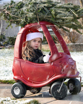 Child In Red Toy Car With Christmas Tree On Top