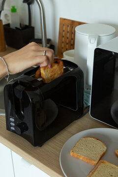 Hand placing bread into toaster making toast breakfast