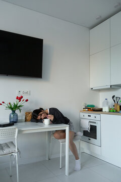 Woman sleeping at kitchen table feeling exhausted