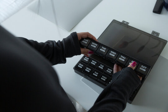 Woman organizing weekly medication using pill box organizer