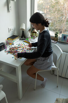 Young woman concentrating on solving jigsaw puzzle