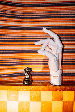 Robot hand reaching for chess piece on board