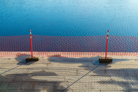 Red safety barrier by waterfront promenade