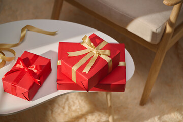 Festive red gift boxes with gold ribbon on a white table