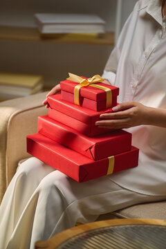 Woman holding a stack of red gift boxes with gold ribbonWoman ho