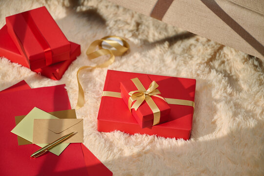 Red gift boxes with gold ribbon on a fluffy rug
