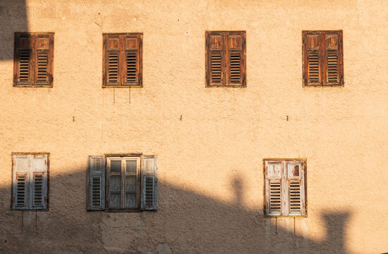 Old Shutters on Peach Stucco Wall with Sunlight and Shadows