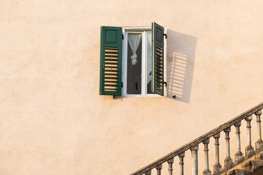 Open Green Shutter Window and Sunlit Staircase on Textured Wall