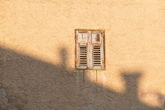 Weathered Wooden Shutters on Yellow Stucco Wall