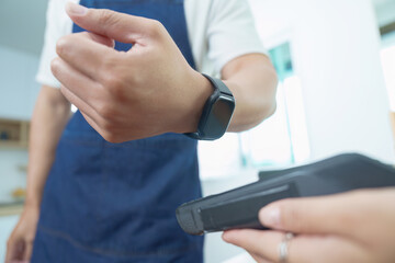 Small Business. Entrepreneur using smartwatch for contactless payment in a modern cafe.