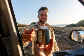 Man sharing coffee outdoors by van
