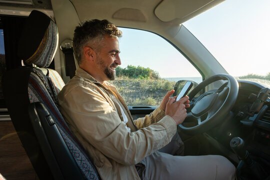 Man smiling while looking at phone in van