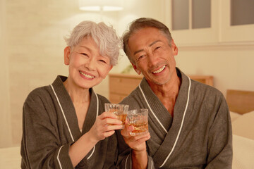 寝室でウイスキーを飲むシニア夫婦　ポートレート　カメラ目線