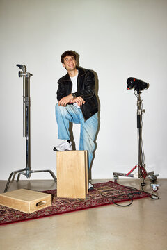 Young man poses confidently in studio setting with props