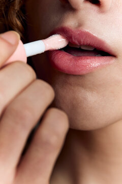 Person applying lip gloss with makeup applicator