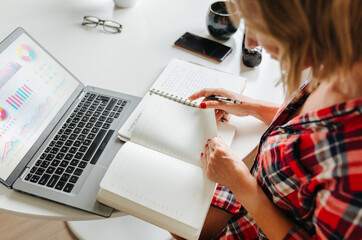 Woman reviewing planner next to data charts on laptop