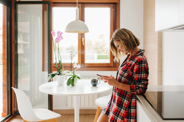 Modern kitchen scene with woman using phone