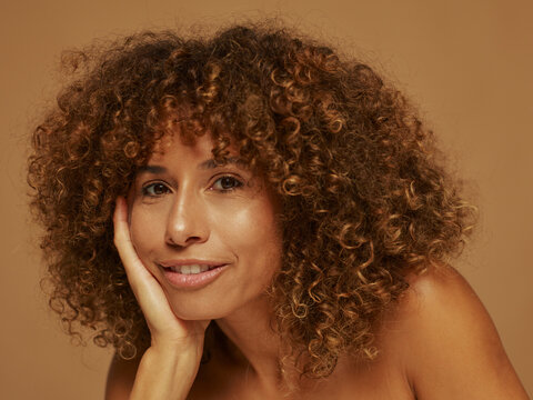 Model With Curly Hair Posing Against a Warm Backdrop