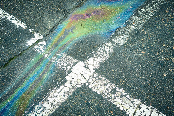 Oil spill creating iridescent rainbow colors on asphalt street